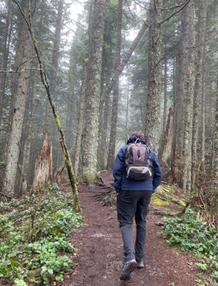 Tyler walking uphill with a backpack wearing hiking pants.