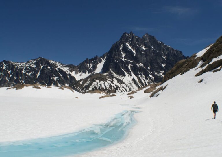 Walking next to the blue waters of Lake Ingalls, surrounded by tall mountain peaks.