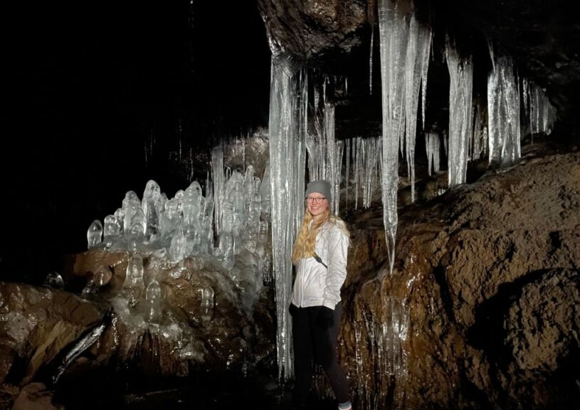 Myself standing near a large icicle in a cave.