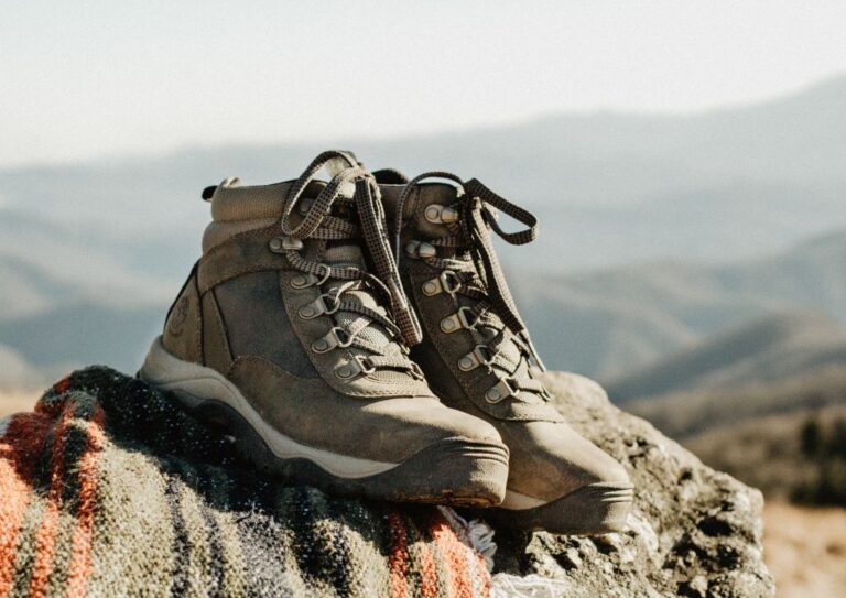 A pair of hiking boots sitting on top of a rock, not being worn by anyone.