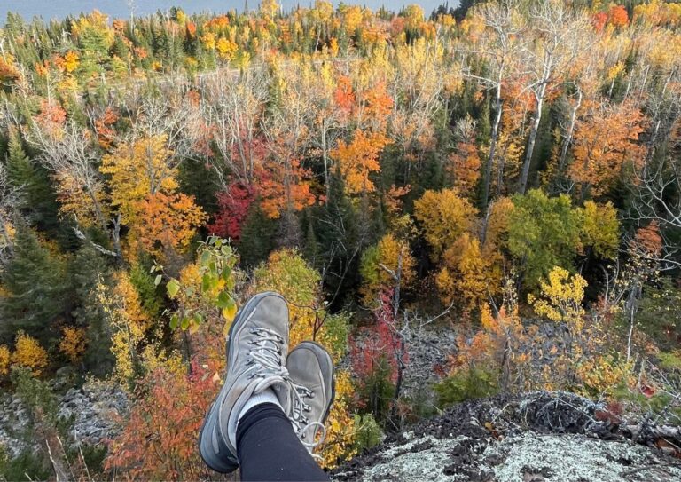 A pair of hiking boots under $100 near a cliff over trees.