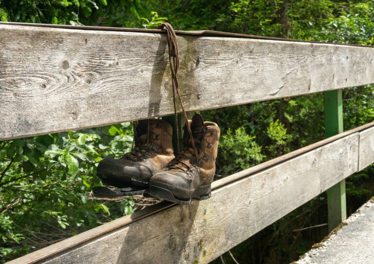Hiking boots that need to be replaced hanging on a fence.