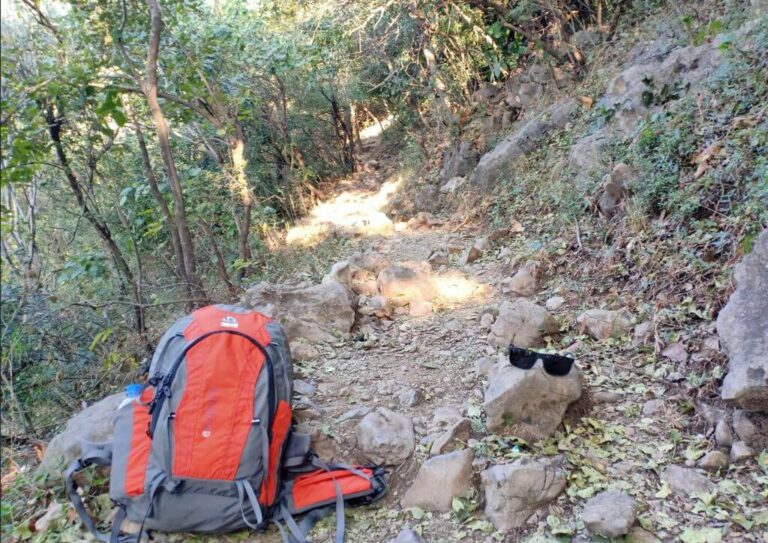 A backpack laying on a rocky trail that can be the cause of knee pain after hiking.