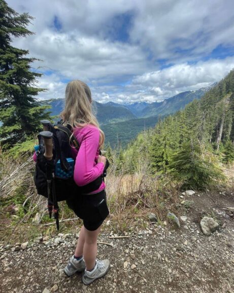 Myself hiking in the mountains with a black backpack on my back.