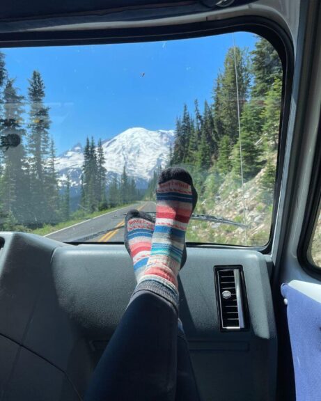 My favorite Smartwool socks on the dash of a car with a mountain in the background.