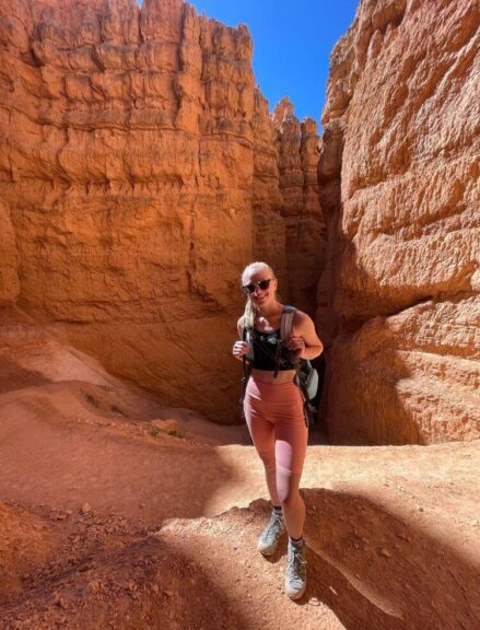 Myself standing in a canyon in Bryce Canyon with towering orange rock walls next to me.