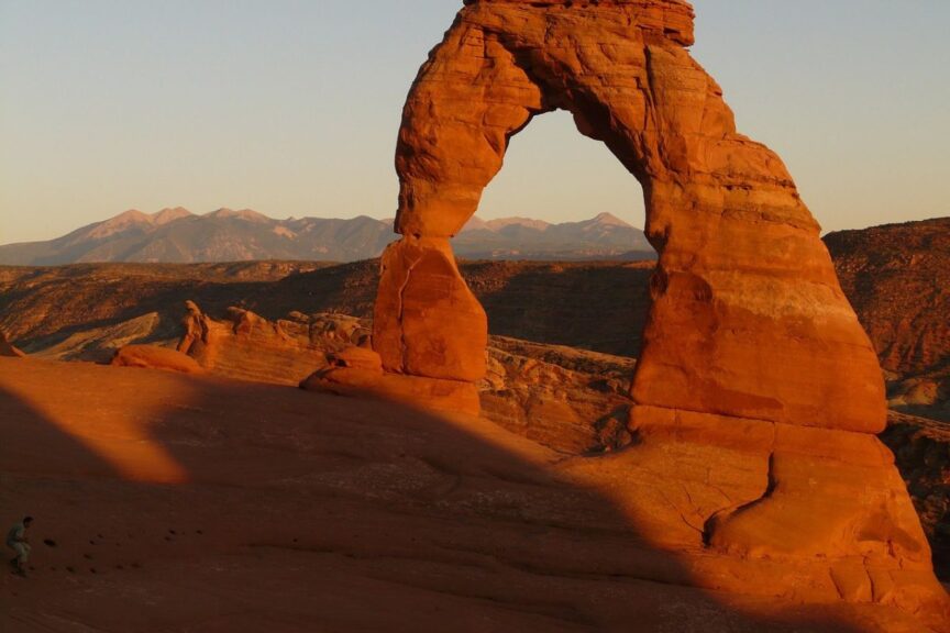 Delicate Arch in Arches National Park at sunrise with the sun casting on the arch.